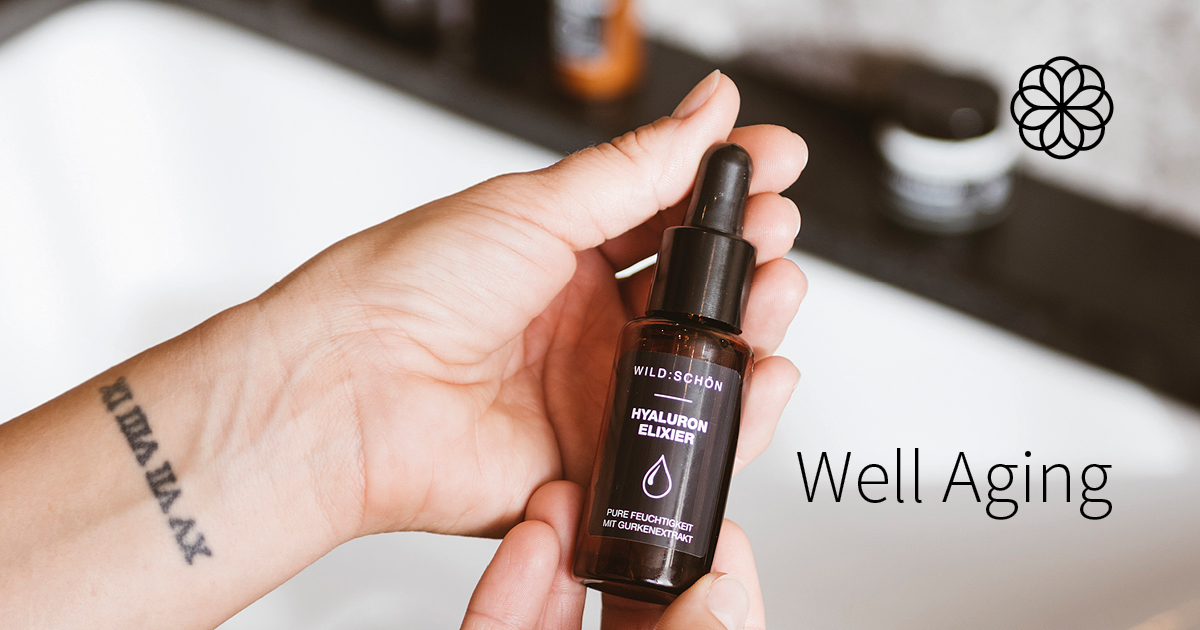 Nahaufnahme einer Hand, die ein Hyaluron-Elixier mit Pipette hält. Text: „Well Aging“ – Fokus auf natürliche Hautpflege.
