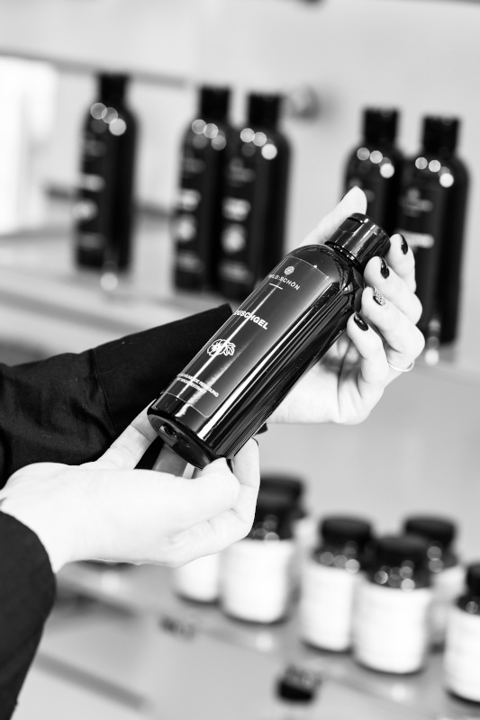 Wildschön Duschgel Person hält eine Flasche Duschgel in den Händen, im Hintergrund Regale mit weiteren Pflegeprodukten.